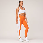 Agni Flow – calças de yoga laranja com faixa lateral branca, vista de corpo inteiro