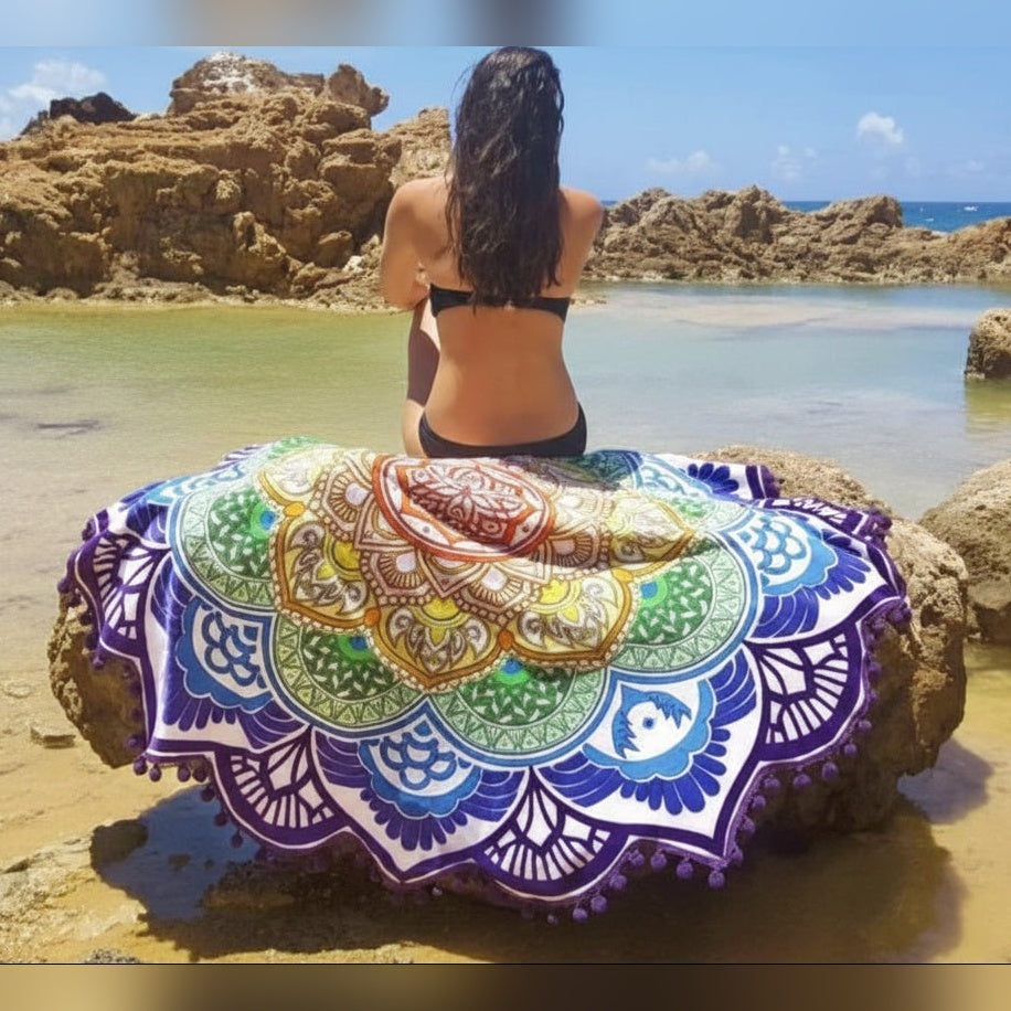 Tapeçaria redonda Mandala Flow colorida com mulher sentada à beira-mar – lifestyle