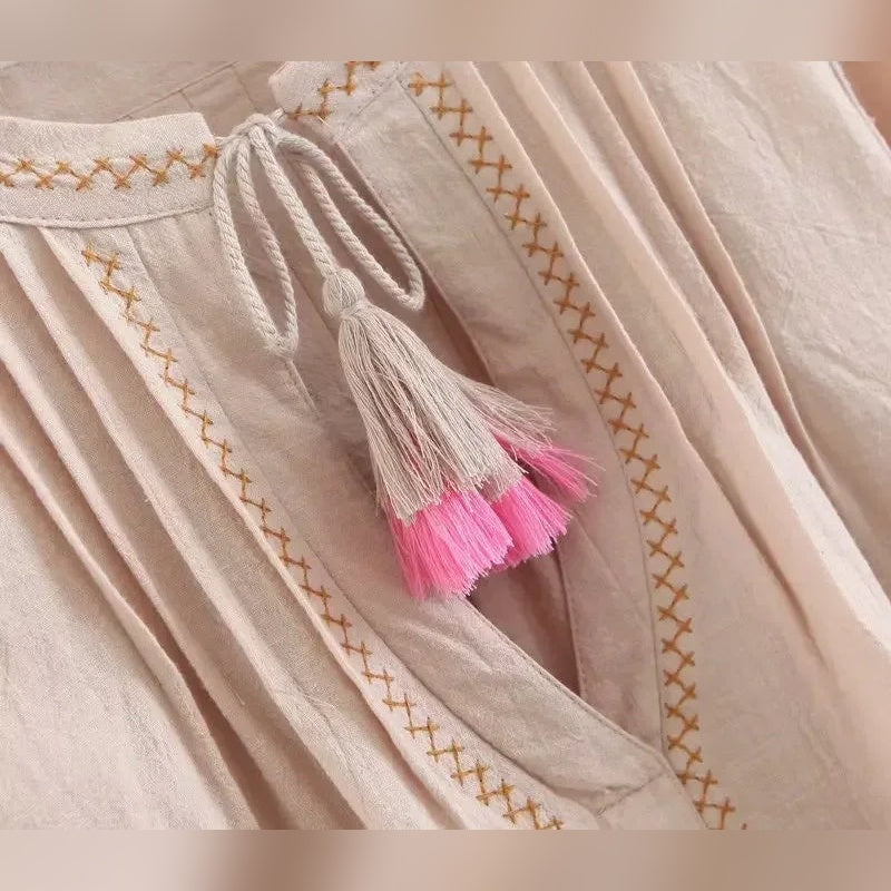 Cordão com borlas rosa no decote da blusa Flora Nomad bege – detalhe