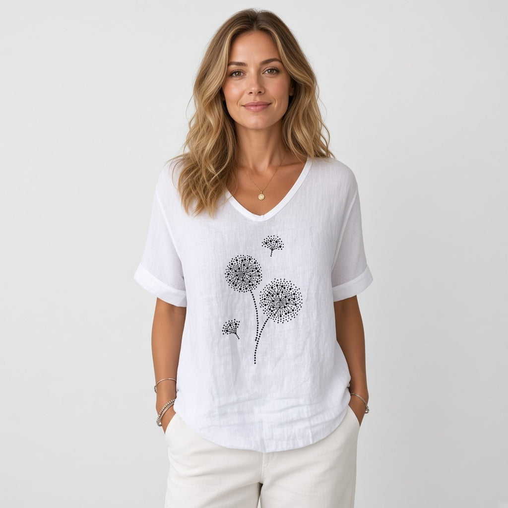 Aura Breeze Blouse – Leveza e Feminilidade – fotografia de estúdio, modelo com blusa branca de decote em V com estampa de dentes-de-leão