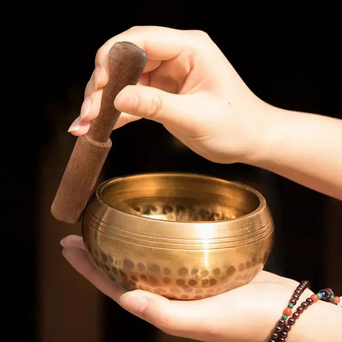 Como tocar a tigela tibetana Dhvani com a baqueta de madeira, pousada na palma da mão