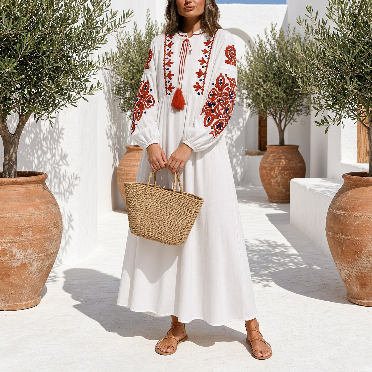 Mulher com o vestido boho Kalinda branco e cesto de palha num pátio de verão