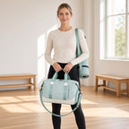 Mala de viagem Destination Flow verde-menta e creme segurada pelas pegas por uma mulher à entrada de um estúdio de yoga luminoso
