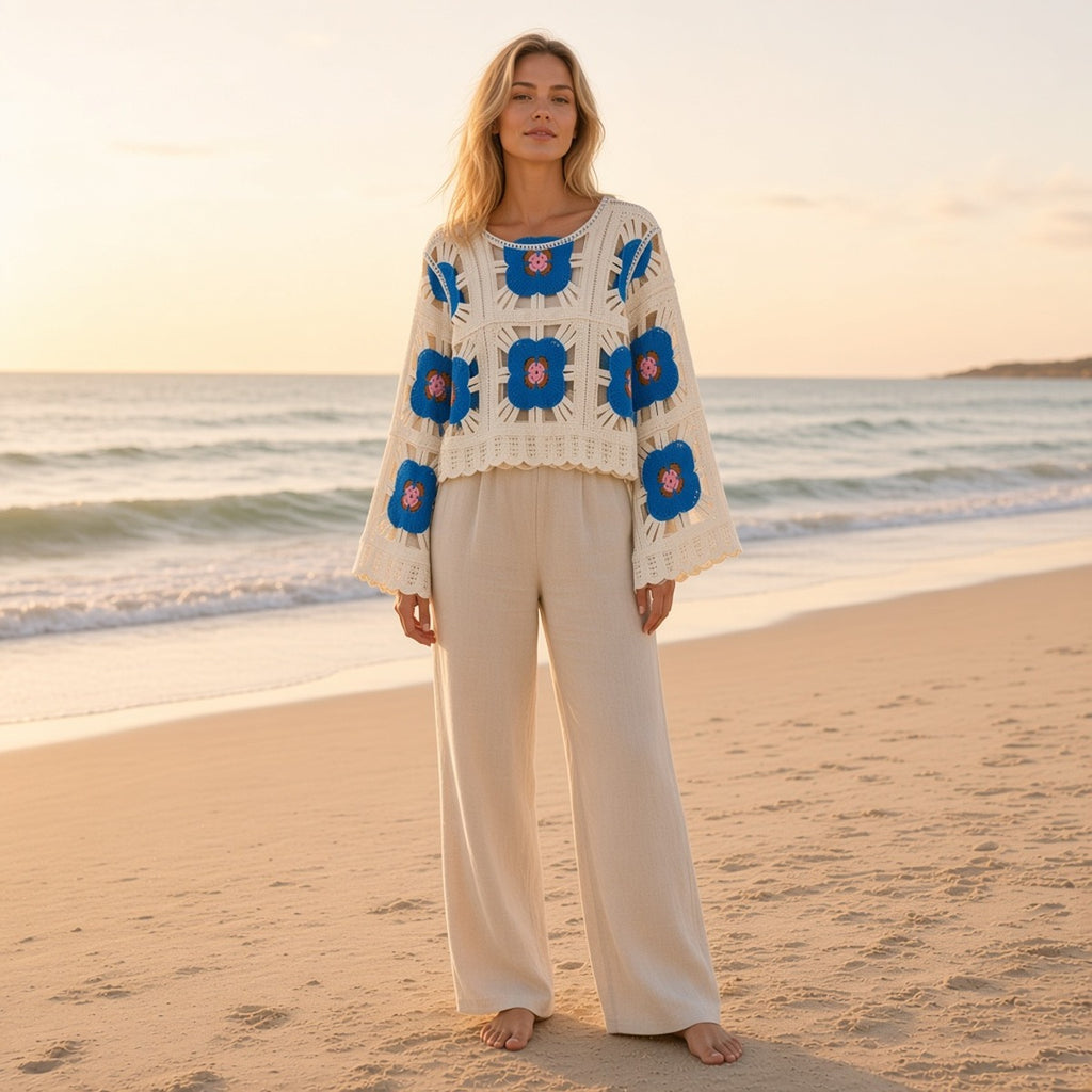 Flora Grace Blouse – Feminilidade Natural – lifestyle numa praia ao pôr do sol, blusa de croché com flores azuis